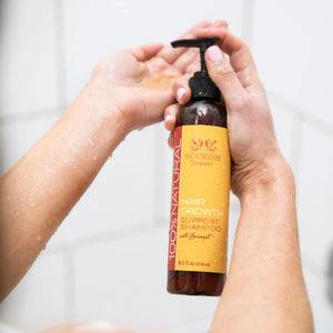 Pumping 100% Natural Hair Growth Support Shampoo onto hands in the shower