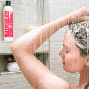 Woman Showering with vision of Vitamins Gold Label, Hair Growth Support Shampoo, with Biotin, Keratin, Saw Palmetto, Baicapil in the background
